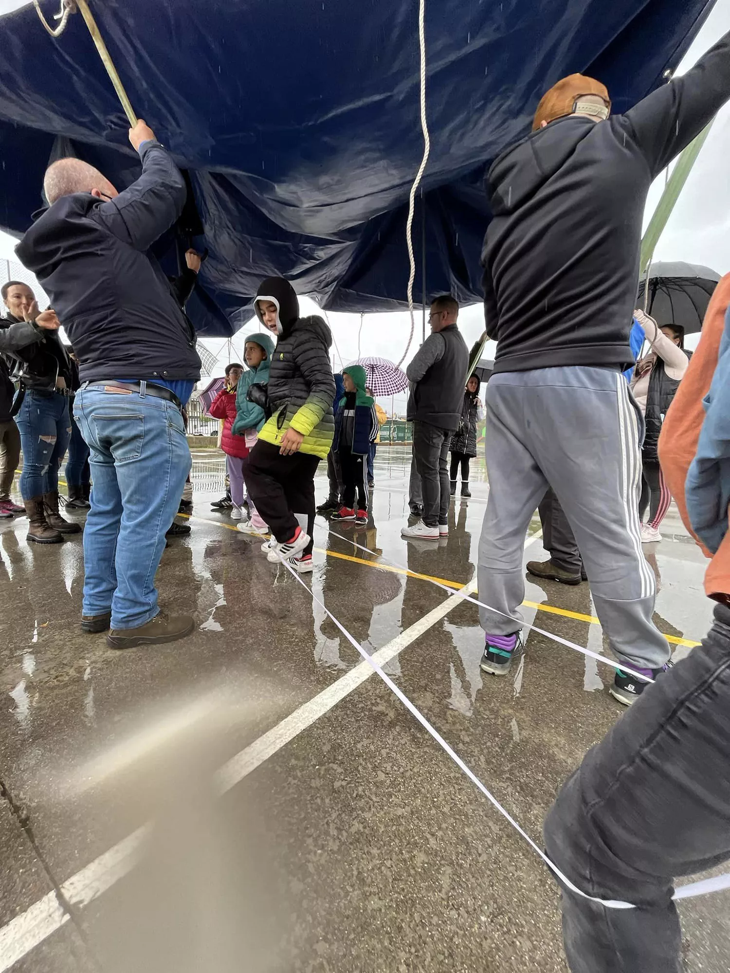 Una lona sirve de techo móvil a los niños del colegio de Columbrianos para disfrutar del recreo a pesar de la lluvia | FOTO: AMPA de Columbrianos