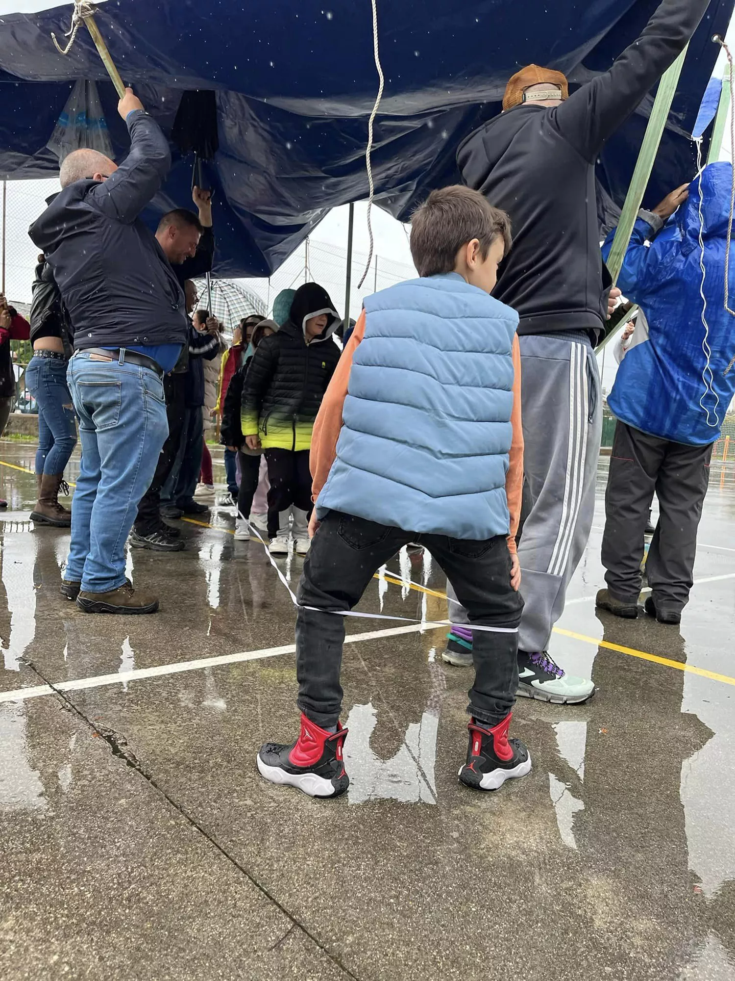 Una lona sirve de techo móvil a los niños del colegio de Columbrianos para disfrutar del recreo a pesar de la lluvia | FOTO: AMPA de Columbrianos