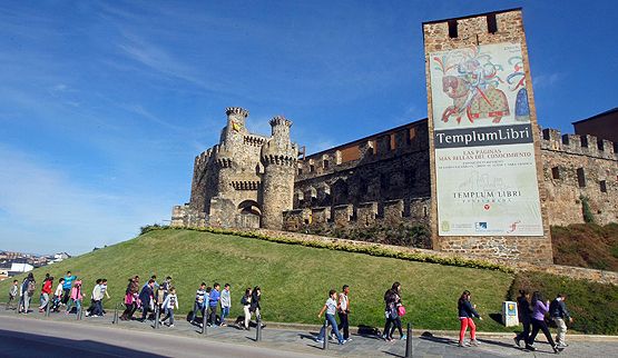 Un grupo de escolares pasan junto a la torre del Castillo con el mural promocional (César Sánchez)